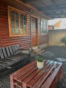 eine Holzhütte mit einer Bank und einer Tür in der Unterkunft Cabaña AlbaMarina - Pichilemu in Pichilemu