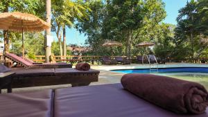 a swimming pool with two beds and umbrellas at Baan Sawasdee Resort in Ko Lanta