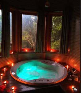 a large bath tub in a room with windows at Chalés Cantinho do Céu in Monte Verde