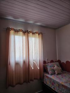 une chambre avec un lit et une fenêtre avec des rideaux dans l'établissement Casa da Família Flores, à Rosário do Sul 7 autres photos