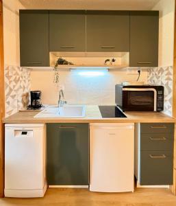 una cucina con lavello e microonde di Evasion Douce Désign a Prénatier