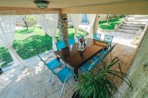 an outdoor dining room with a table and blue chairs at Villa Marijana in Zmijavci
