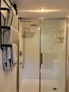 Un baño con ducha con puerta de cristal en Tui Bush Chalet, en Parakakau 27 fotos más