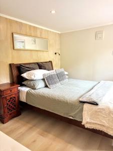 1 dormitorio con 1 cama con mesita de noche y espejo en Tui Bush Chalet, en Parakakau