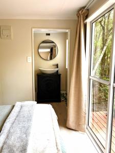 Un baño con una cama, un lavabo y un espejo. en Tui Bush Chalet, en Parakakau