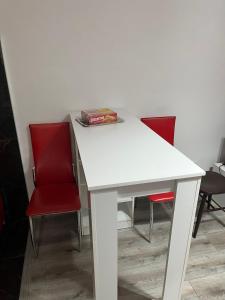a white table with two red chairs and a book on it at Apartman Jovanović in Belgrade