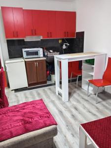 a kitchen with red cabinets and a white table at Apartman Jovanović in Belgrade