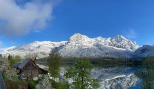a cabin on the shore of a lake with snow covered mountains at Ferienhaus s'Mosern in Grundlsee