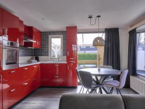 a kitchen with red cabinets and a table with chairs at t Kaatsheuveltje 7 in Kaatsheuvel