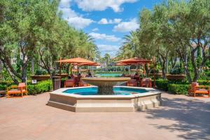 ein Brunnen mit Stühlen und Sonnenschirmen in einem Park in der Unterkunft New Luxury 1BR Stay in the Heart of Irvine in Lake Forest