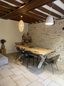 a dining room with a wooden table and a brick wall at Le grand Brandonné in Loiré