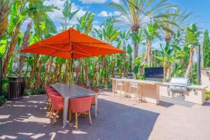 ein Tisch und Stühle mit einem orangefarbenen Sonnenschirm auf einer Terrasse in der Unterkunft New Luxury 1BR Stay in the Heart of Irvine in Lake Forest