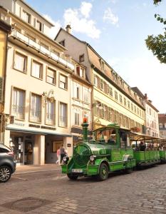a green bus parked on a street in front of buildings at Appartement duplex climatisé avec terrasse "HANSI" in Colmar