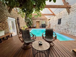 a wooden deck with chairs and a swimming pool at Le grand Brandonné in Loiré