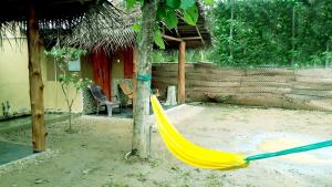 una hamaca amarilla frente a una casa en Golden Nature Cottage, en Udawalawe