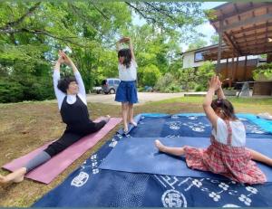 three girls doing yoga on mats in a yard at Private Forest Cottage for Two, Organic Lifestyle in Bungoono