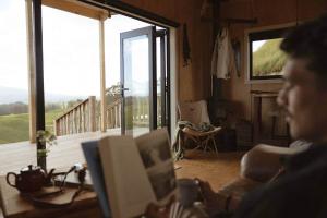 Una mujer sentada en un sofá en una habitación con una computadora portátil. en Sunsets, outdoor bath, mountain views, fire pit, en Marotiri