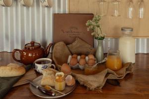 Una mesa con huevos y pan y una caja de leche. en Sunsets, outdoor bath, mountain views, fire pit, en Marotiri