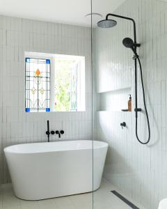 a white bathroom with a tub and a window at Bruns Surf Shack in Brunswick Heads