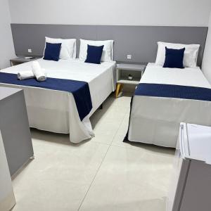 two beds with blue and white pillows in a room at Melges Apart Hotel in Pontes e Lacerda +8 photos