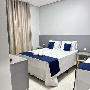 a bedroom with a large bed with blue and white pillows at Melges Apart Hotel in Pontes e Lacerda