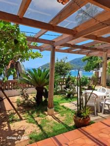 eine Holzpergola mit Blick aufs Wasser in der Unterkunft Pousada Manaca in Abraão