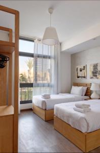 Luxury Stays in Cairo Festival City في القاهرة: غرفة نوم بها سريرين ونافذة كبيرة +283 صورة