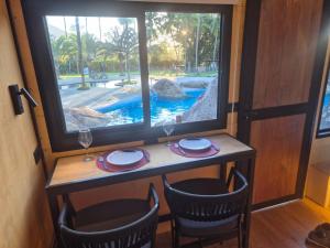 a table with chairs and a window with a view of a pool at Camping & Cabanas Ilhabela in Ilhabela +59 photos