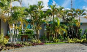 a building with palm trees in front of it at Mana Beach Experience B019 in Porto De Galinhas