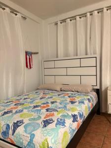a bedroom with a bed with a colorful comforter at Puerta al Tren apartamento in San Juan