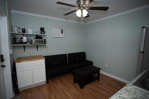un soggiorno con divano nero e ventilatore a soffitto di Guest House Near Everything ad Augusta Altre 4 foto