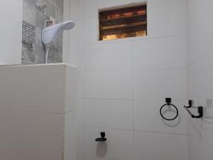 a white tiled bathroom with a sink and a window at Pousada e Restaurante Morro Alto in São João Batista do Glória