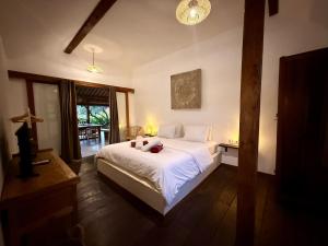 a bedroom with a bed with white sheets and a window at Joglo Villas Uluwatu - Tropical Oasis in Uluwatu