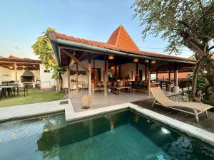 a house with a swimming pool in front of it at Joglo Villas Uluwatu - Tropical Oasis in Uluwatu