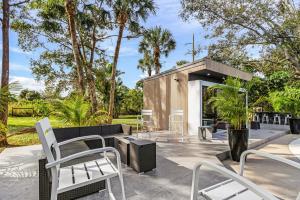 een patio met witte stoelen, tafels en bomen bij The oak house in Naples