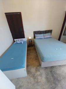 Kitnet - quarto - privativo في إتوبيفا: سريرين في غرفة صغيرة ذات أغطية زرقاء