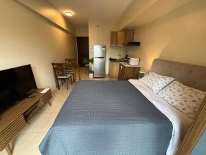 a bedroom with a large bed and a kitchen at Cebu AvidaRiala Condotel by Go2Stays in Cebu City