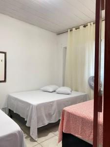 ein weißes Zimmer mit zwei Betten und einem Fenster in der Unterkunft Quarto Triplo Bougainville 2 in Areia