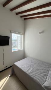 Una habitación blanca con una cama y una ventana en Apartamento en Santa Fe, en Santa Fe de Antioquia