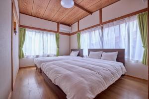 a bedroom with a large bed with white sheets and windows at APROStay富士河口湖小立17 in Fujikawaguchiko +82 photos