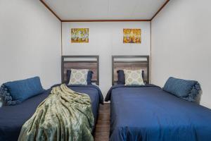 twee bedden in een kamer met blauwe lakens en kussens bij Rustic Lakefront Cottage with Fire Pit and Scenic Views in Brechin