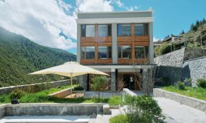 a house on a hill with an umbrella at Siguniang Mountain Waiting for the Wind Snow Mountain Guesthouse in Mount Siguniang +45 photos