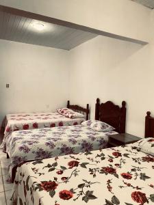 a bedroom with two beds with flowers on them at Suíte Tripla Bougainville 2 in Areia