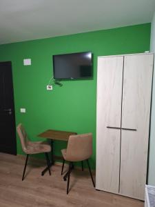 una stanza con un tavolo e sedie e una TV su una parete verde di Popas La Vintu 