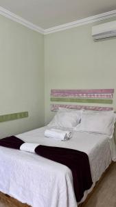 a bedroom with a bed with white sheets and pillows at Pousada Cipó in Serra do Cipo