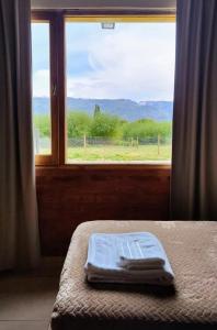 a bed with a towel on it in front of a window at Anlupa Casa in El Bolsón