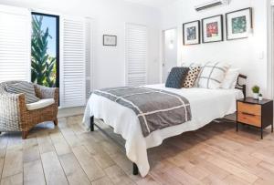 a white bedroom with a bed and a chair at Flagship Villa in Trinity Beach