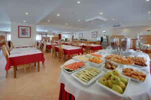 una mesa larga con platos de comida. en Hotel Alba en Monte Gordo