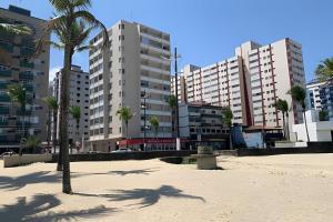 a beach with palm trees in front of tall buildings at Seu apê de férias - Praia Grande in Praia Grande