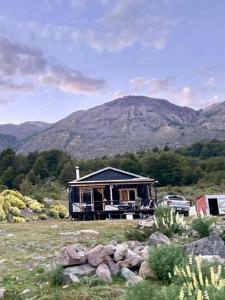 a house in a field with a mountain in the background at Cabaña lago tranquilo, camino valle exploradores in Puerto Tranquilo